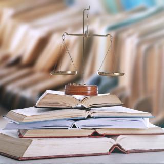 scale of justice on top of open stack of books