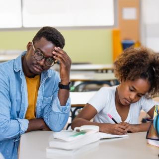 Worried father watches daughter do schoolwork
