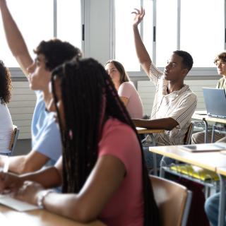 Students raise their hands in multi-ethnic classroom