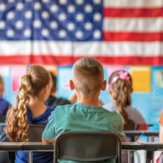 classroom students sitting in front of large American flag