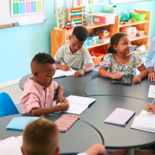 picture of teacher sitting at table with students