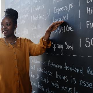 photo of female teacher standing at chalkboard